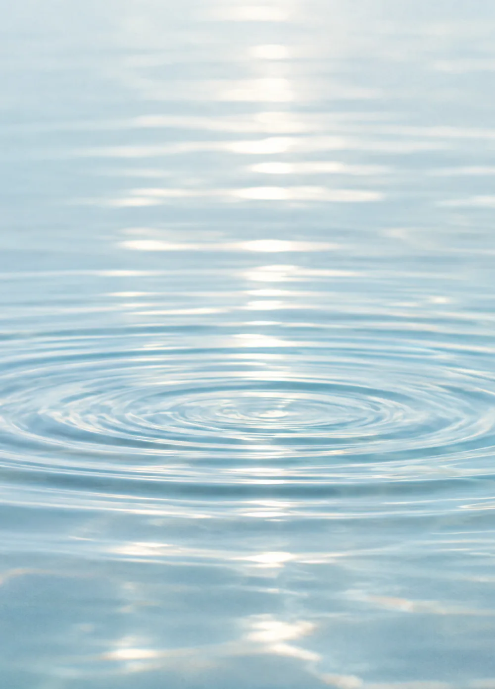 Superficie del agua con ondas concéntricas bajo la luz del sol